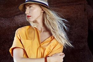 A blonde woman wearing a hat and a yellow blouse