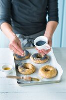 Bagels being sprinkled with poppy seeds for baking