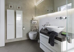 A wash stand with a bowl basin, a corner toilet and a designer radiator in a small bathroom