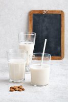 Three glasses of vegan almond milk and almonds