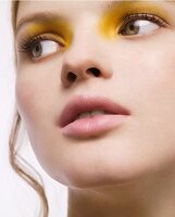 A close-up portrait of a young woman with yellow eyeshadow