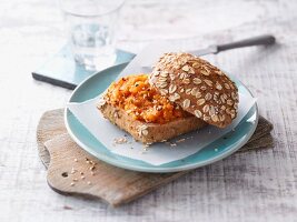 An oat roll with a carrot and sesame seed spread