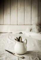 Cutlery in a white jug on a muslin cloth