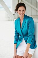 A young brunette woman wearing white shorts and turquoise blazer