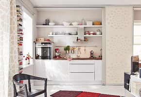 A kitchen niche behind open sliding doors in a one-room apartment