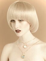 A young woman with platinum blonde pageboy hair style wearing two different length necklaces
