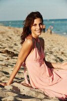 Junge Frau in rosa Sommerkleid am Strand