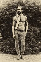 A topless man wearing tweed trousers and a scarf