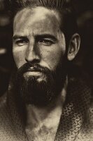 A portrait of a young man with a full beard