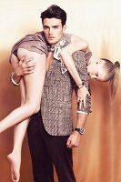 Mann trägt Frau in Minikleid über der Schulter