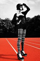 A young woman wearing a black bodysuit and leggings standing on a running track