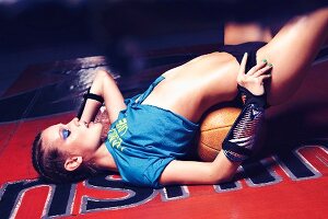 A young woman wearing a cropped top lying on a medicine ball