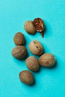 Whole nutmegs and one halved nutmeg on a blue surface