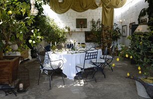 Table festively set with white tablecloth and lemon tree in planter