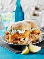 A fish sandwich with tartar sauce and coleslaw