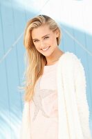 Junge blonde Frau in Shirt mit Sternenmotiv und weisser Strickjacke