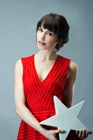 Dark-haired woman wearing red sleeveless dress holding star