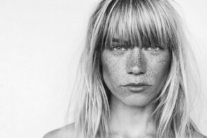 A young, light-blonde woman with lots of freckles (black-and-white shot)