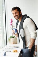 A man standing by a table with a laptop, coffee and pastries