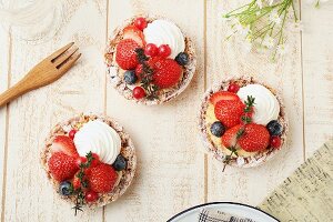 Strawberry tartlets with blueberries, redcurrants and cream (seen from above)