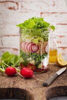 A layered salad with peas, radishes, cucumber and tomatoes in a ja