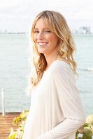 Junge blonde Frau in hellem Oversize-Shirt am Meer