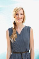 A young woman wearing a grey sleeveless pleated dress