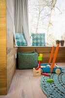 Modern wood-clad walls, window seat and wooden toys on oak floor in corner
