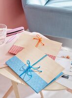 Homemade folders made from wood veneer decorated with strips of paper and bows