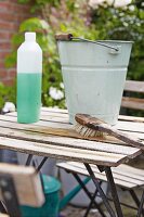 Frühjahrsputz auf der Terrasse, Vintage Metalleimer und Putzutensilien auf Gartentisch