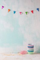 A stack of paper cases on a white surface beneath colourful bunting