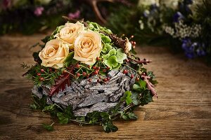 Alpine-style arrangement of cream roses and bark