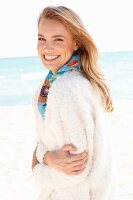 A young woman on a beach wearing a fluffy white jacket