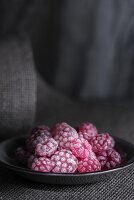 Raspberry sweets in a grey plate on a piece of grey fabric