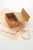 Presents being made: a cardboard box being covered with shiny paper