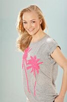 A young blonde woman wearing a grey sequinned T-shirt with palm trees
