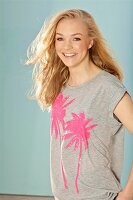 Young blonde woman wearing a grey sequinned T-shirt with palm trees
