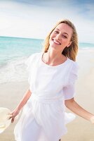 Frau in weißem Chiffonkleid am Strand