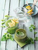 Two green smoothies garnished with citrus skewers and lamb's lettuce