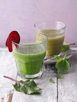 Two green smoothies garnished with beetroot and basil