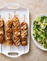 Grilled scallops wrapped in bacon on skewers with a fennel and apple salad