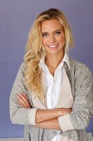 A young blonde woman wearing a white blouse and a grey shirt jacket