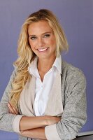 A young blonde woman wearing a white blouse and a grey shirt jacket