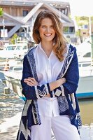 A young brunette woman wearing a white blouse and a blue-and-white cardigan