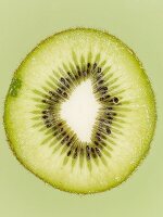 Aufgeschnittene grüne Kiwi vor grünem Hintergrund, Close-Up