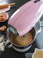 A pink KitchenAid working with baking ingredients in a stainless steel mixing bowl
