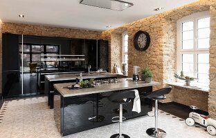 Moderne Küche mit schwarzen Hochglanzoberflächen und zwei freistehende Theken in rustikalem Altbau mit Sandsteinwänden