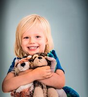 Blonder Junge mit Kuscheltieren im Arm