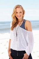 Junge blonde Frau in Tanktop und Netzpulli am Strand