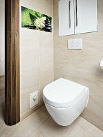 weiße Toilette unter Einbauschrank und Fotokunst an Fliesenwand